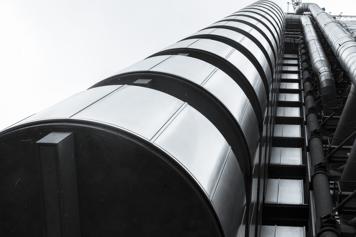 The Lloyd's building, its external escalators and service ducts seen close up against a pale sky.